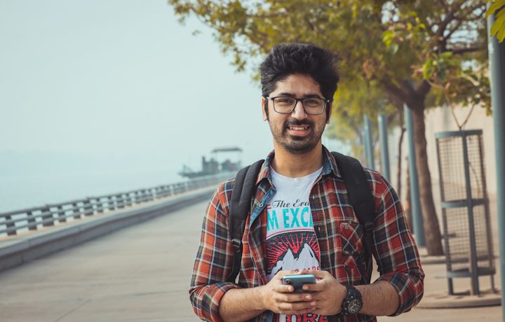 A young man smiling while holding his phone
